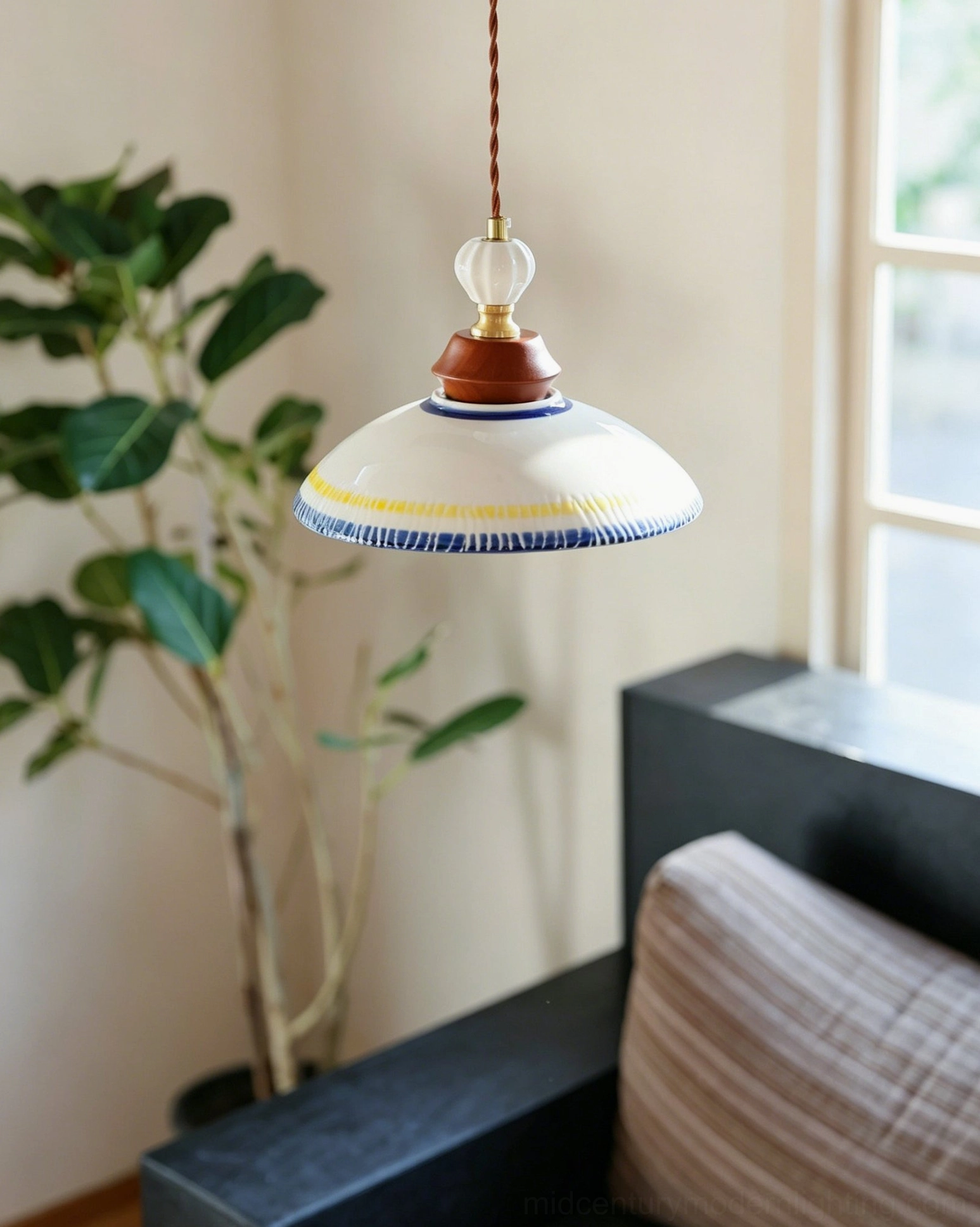 Tilly ceramic pendant light hanging in warm rustic living room setting with dark sofa and potted plant, low-angle side perspective