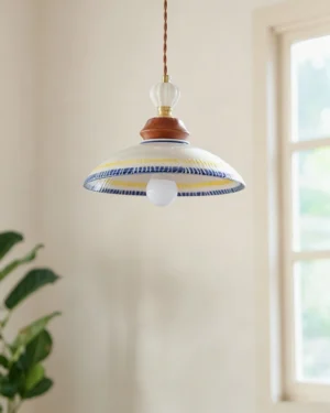 Tilly ceramic pendant suspended by brown twisted cord with exposed vintage Edison bulb, three-quarter view showing hardware and natural window lighting