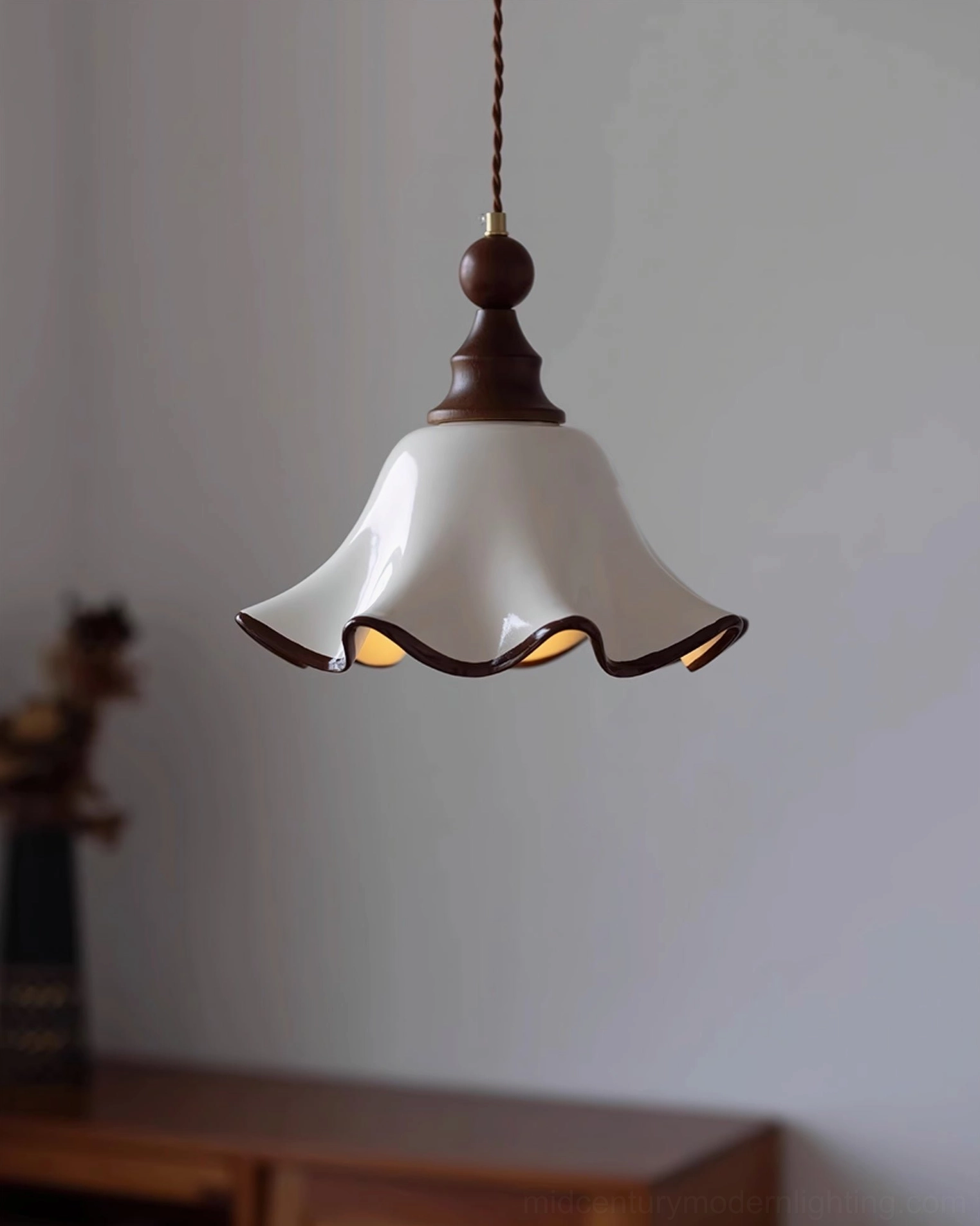 Ceramic ruffled Toledo pendant light with dark brown metal fixture over vintage wooden furniture