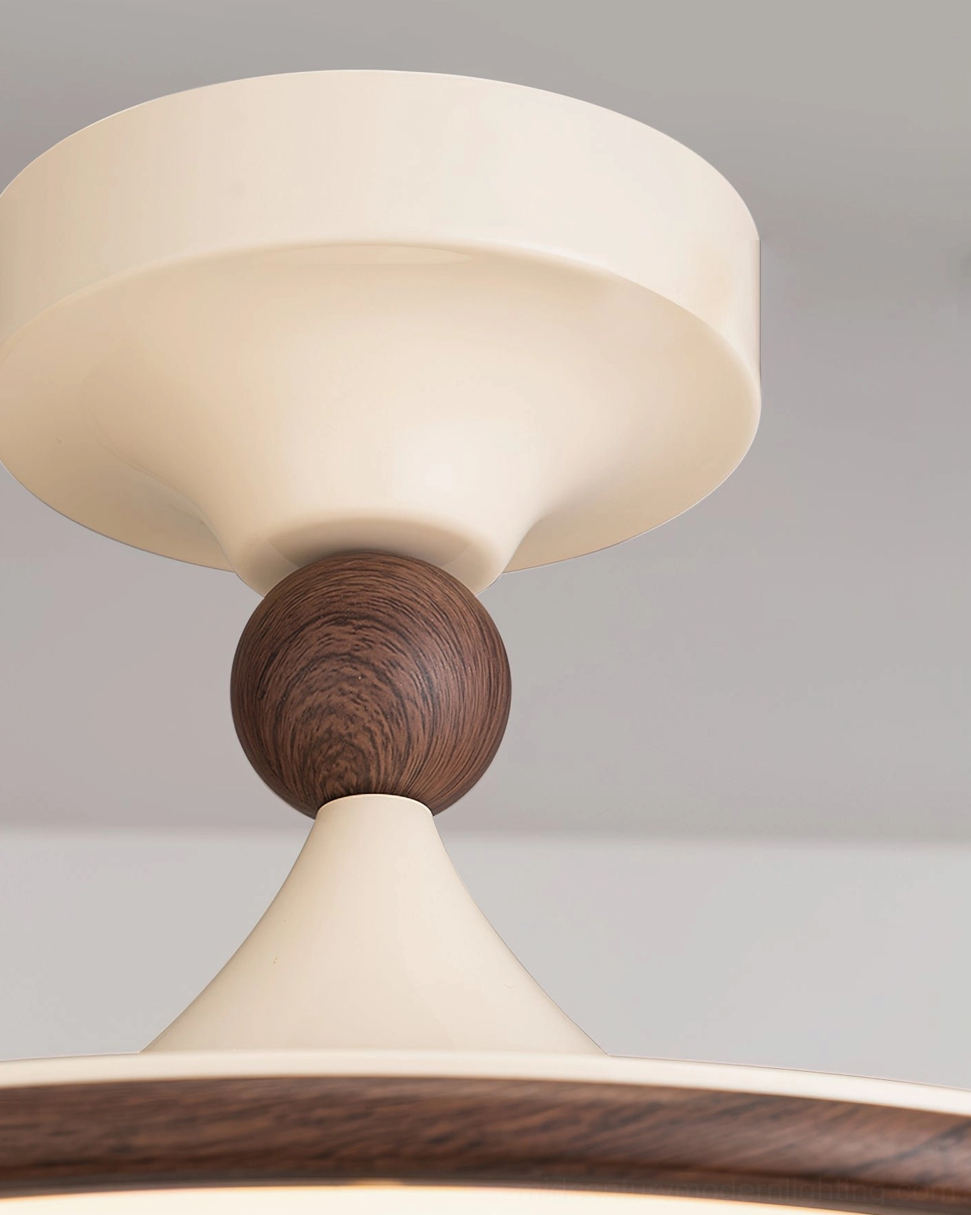 Close-up of Tomaso ceiling light mounting joint featuring cream curved base and round walnut wooden decorative ball