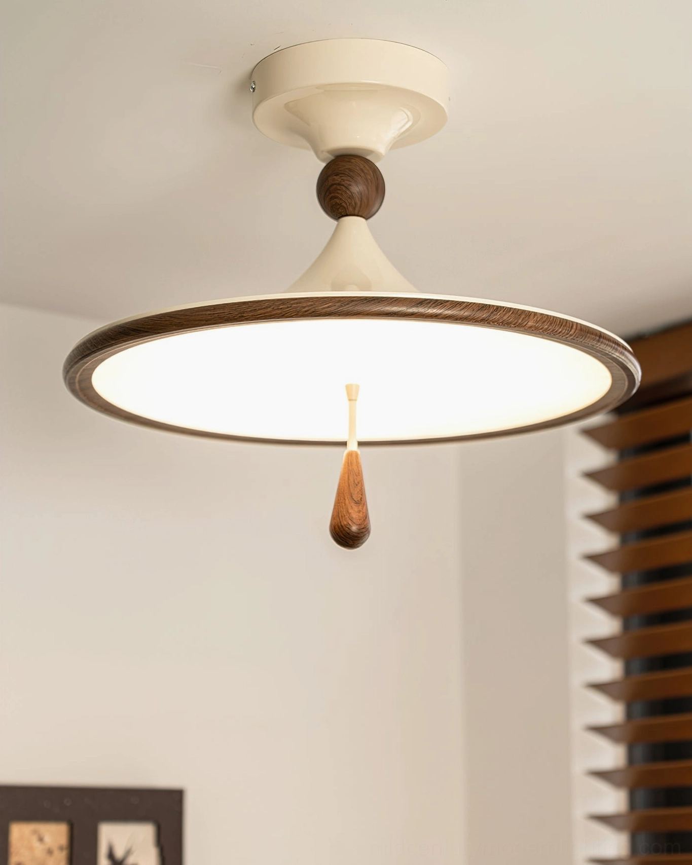 Tomaso flush mount ceiling fixture lit with diffuser panel glowing, walnut teardrop pull visible, three-quarter view