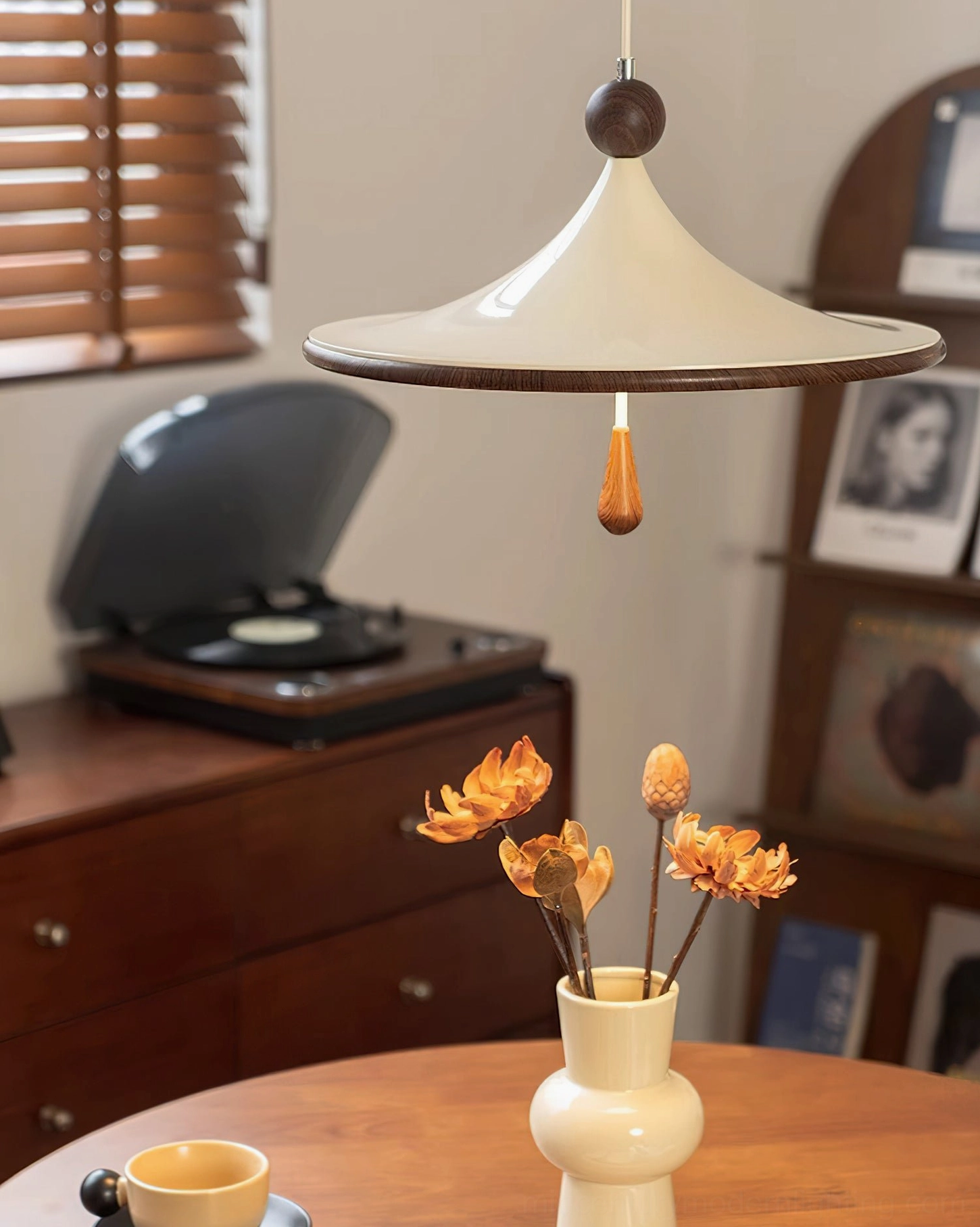 Tomaso pendant hanging over wooden dining table with floral centerpiece demonstrating warm home styling