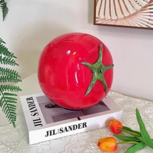 Red tomato glass lamp on bedroom dresser with fashion book and tulip decoration, three-quarter view