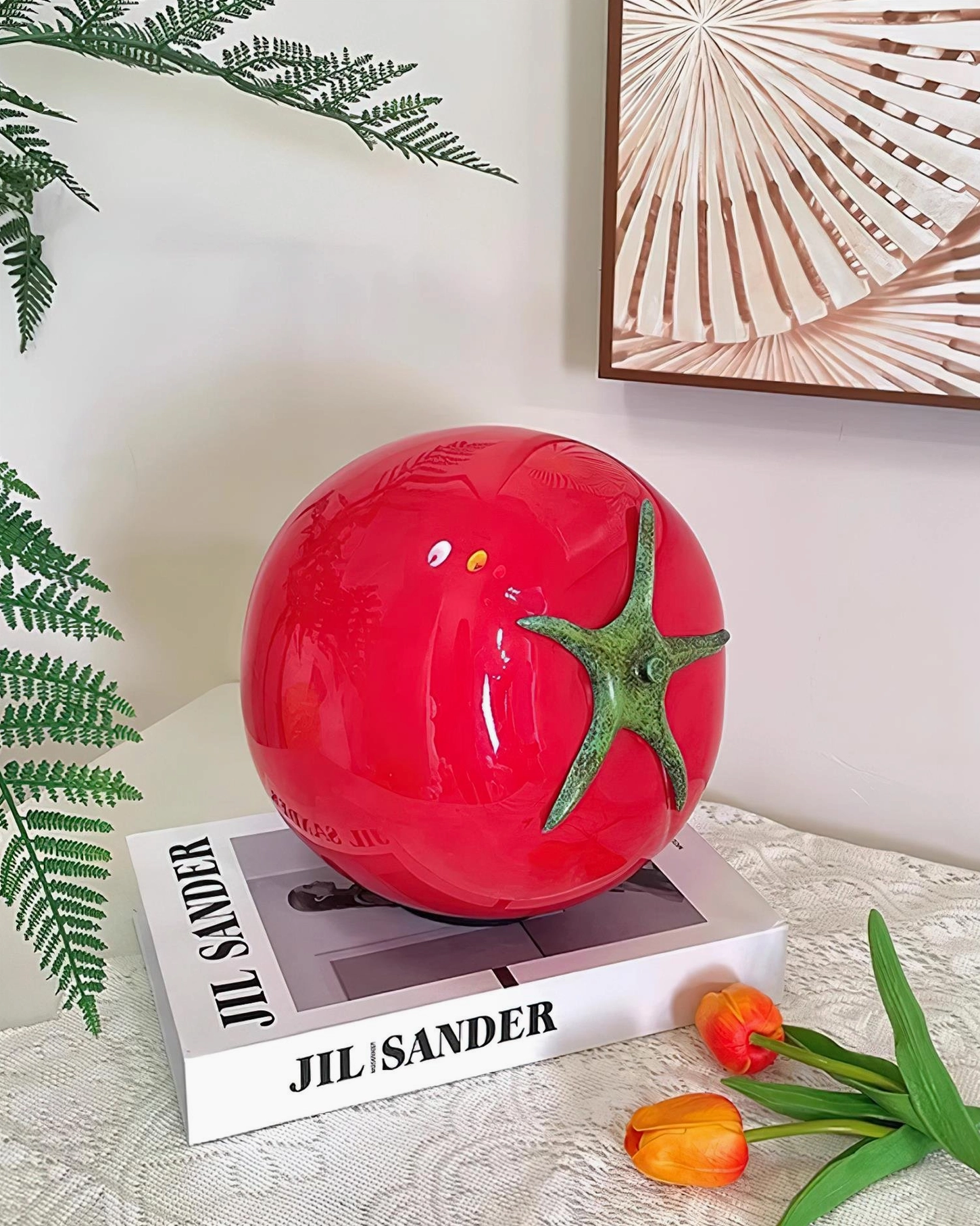 Red tomato glass table lamp on bedroom dresser with fashion book and fern plant decoration
