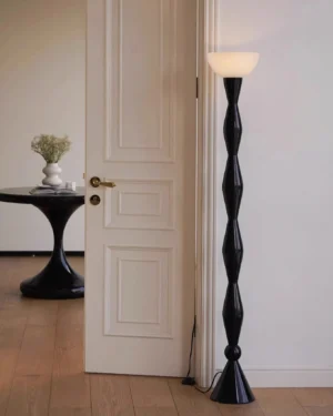 Black metal floor lamp with twisted column in minimalist entryway with small side table, neutral home decor