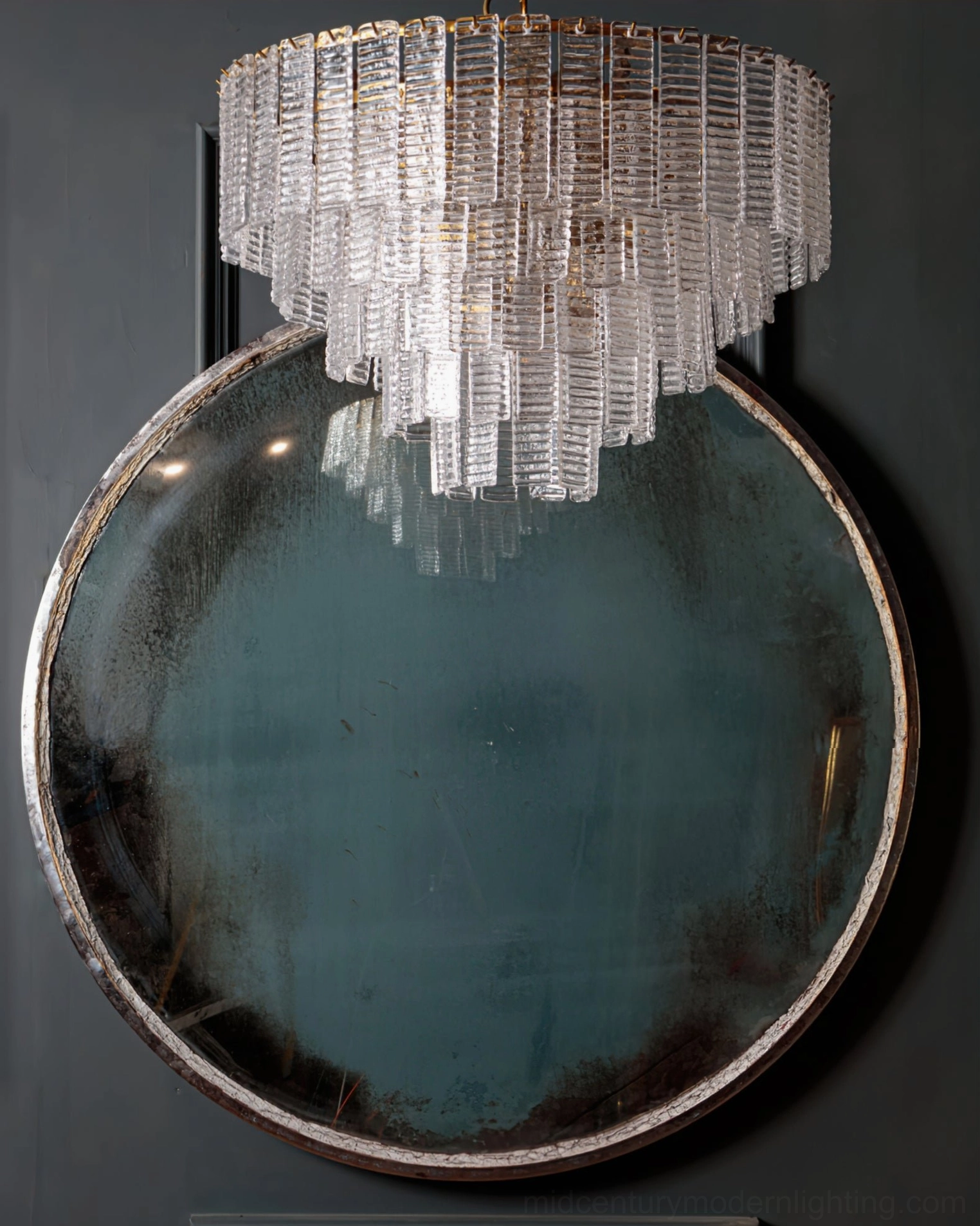 Clear Toronto chandelier overhead view with tiered glass design above round vintage mirror and grey wall
