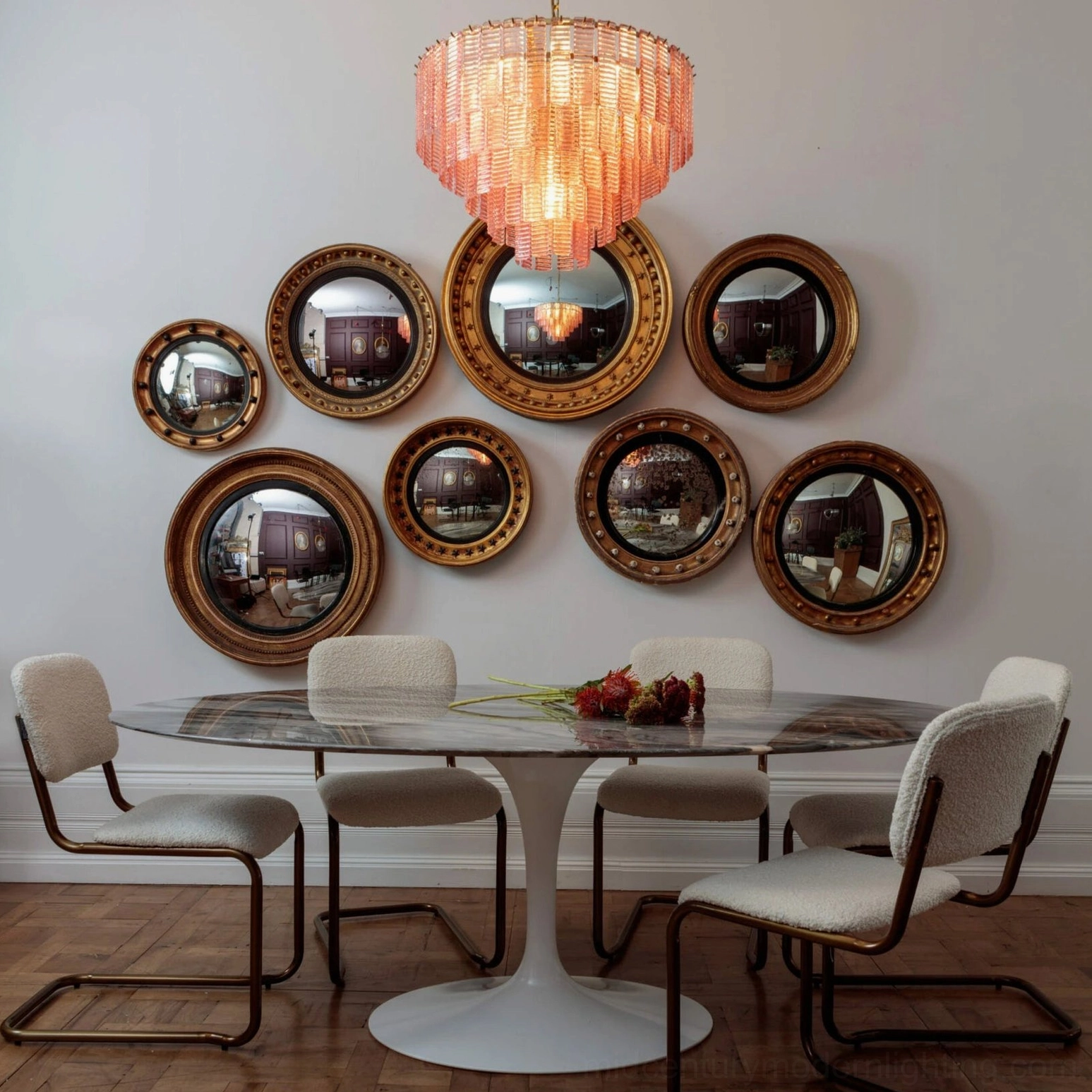 Illuminated pink tiered Toronto chandelier in formal dining room with gold mirrors and modern furniture