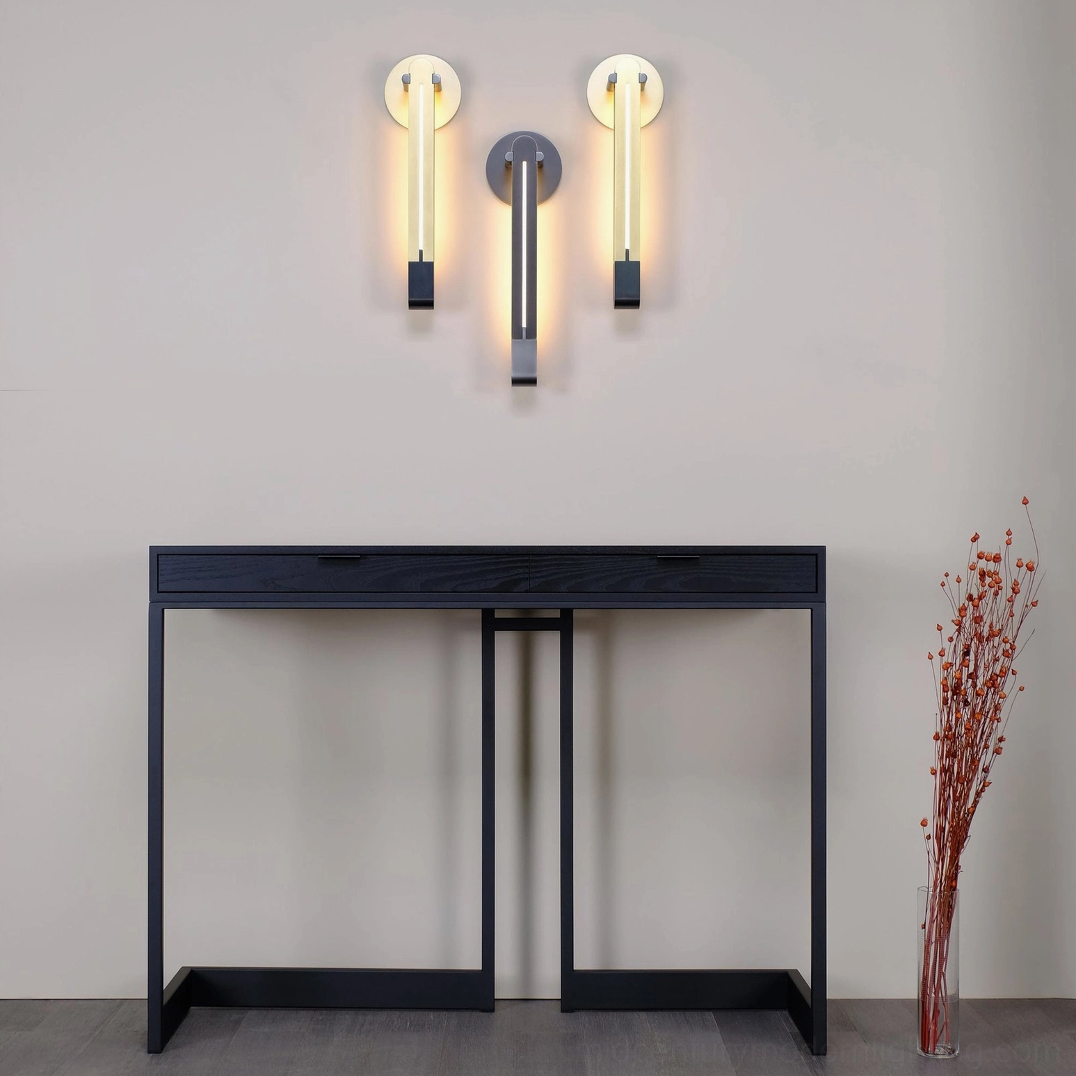 Three Torpedo sconces in mixed black and brass finishes installed in hallway with black console table creating modern minimalist gallery wall