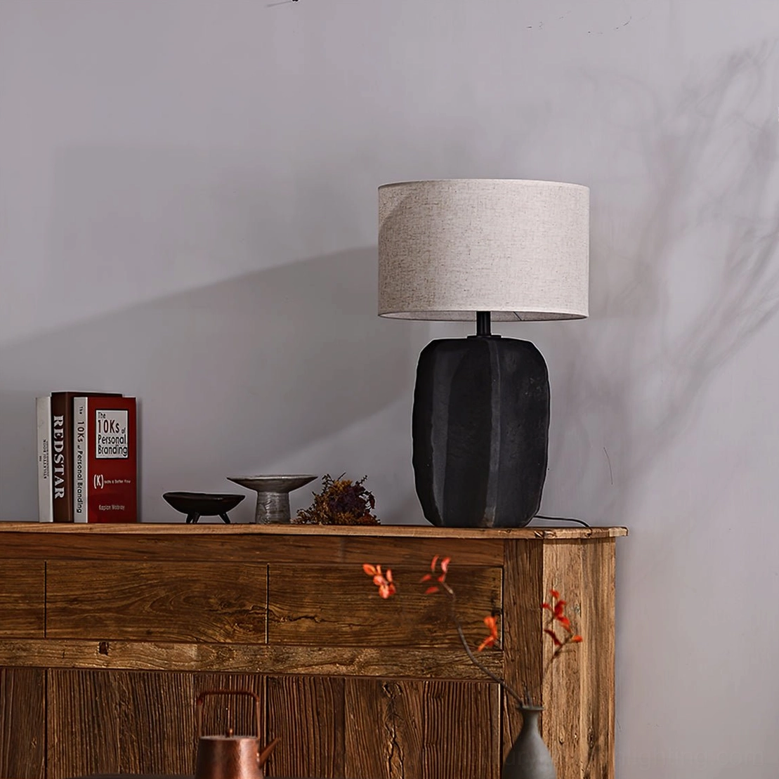 Torso lamp with grey beige fabric shade on wooden sideboard with decorative plants