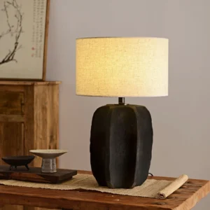 Torso modern table lamp with warm ambient light on wooden dining table with tableware