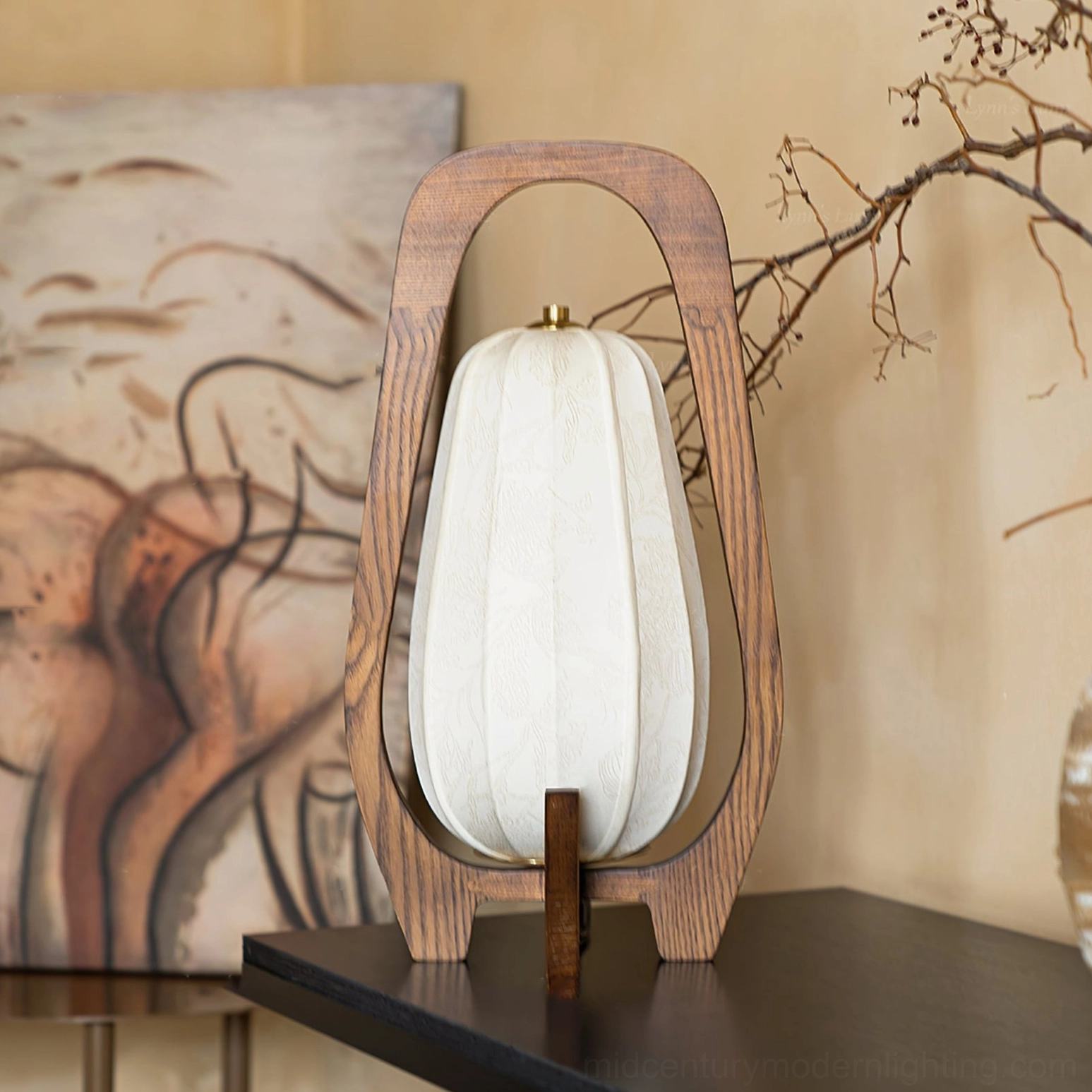 Totem wood table lamp on dark tabletop with framed artwork, rear three-quarter view showcasing wood construction