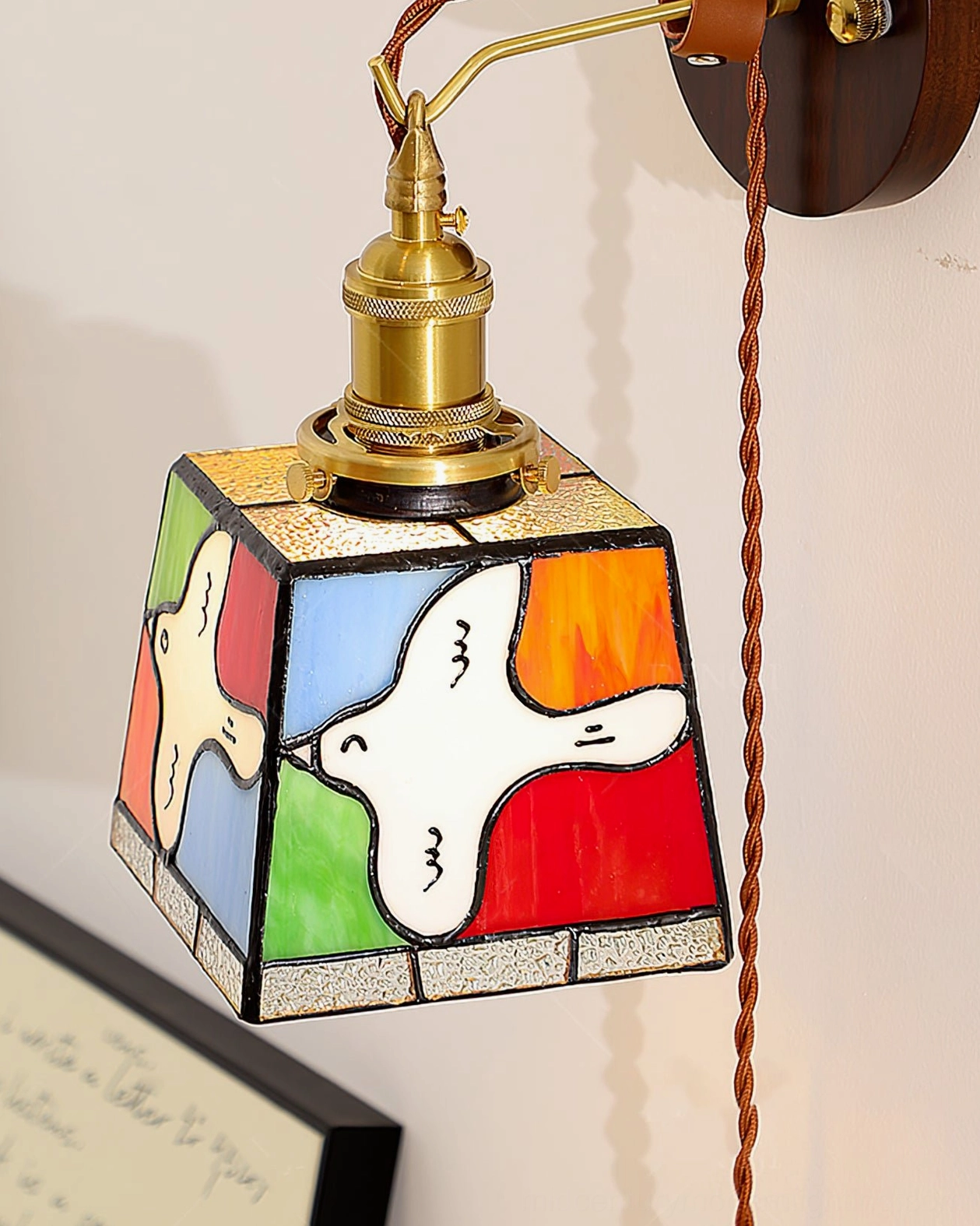 Trapezoid stained glass dove wall lamp with exposed twisted cord hanging on light-colored interior wall