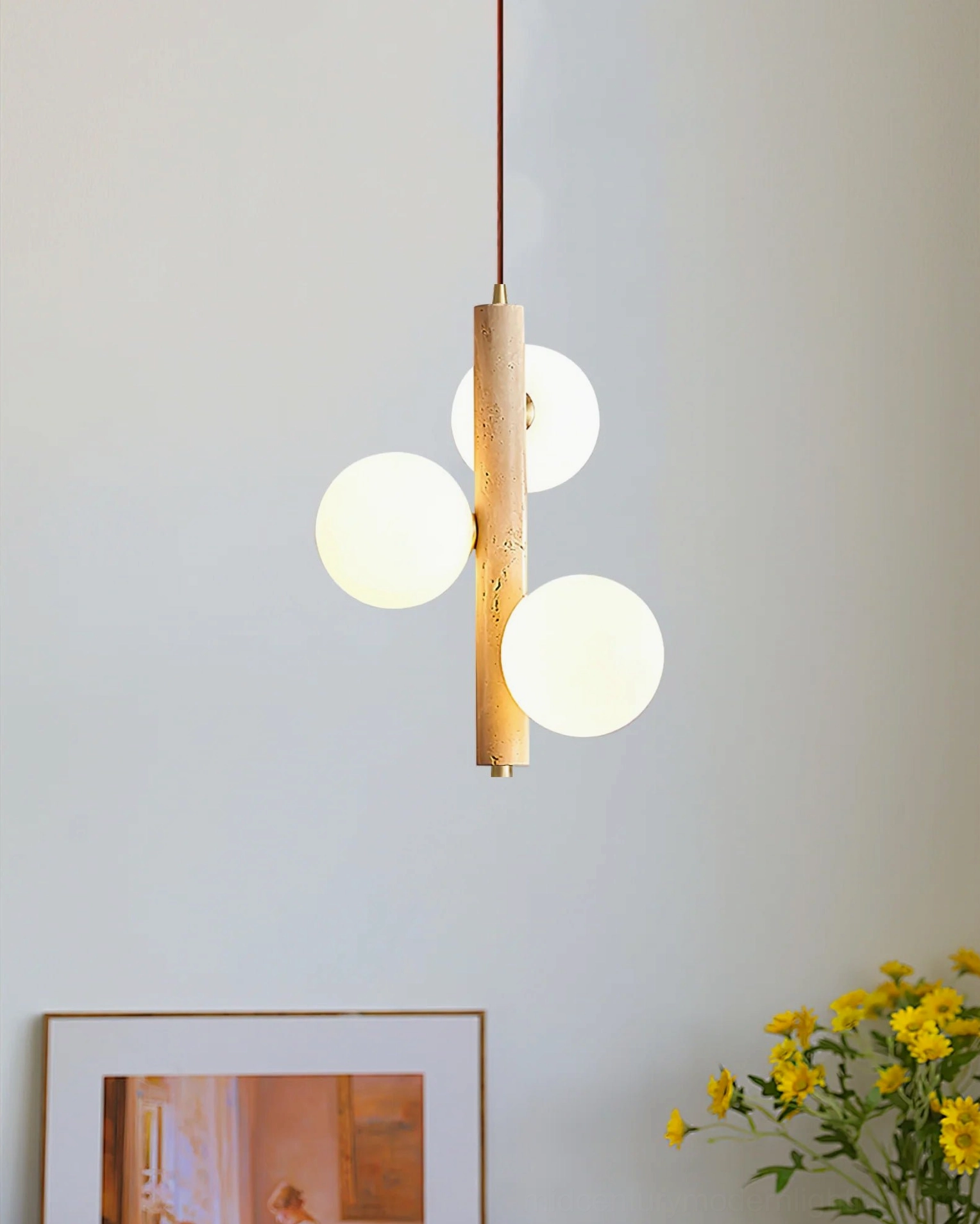 Three-head travertine pendant lamp in bohemian home corner with artwork and flowers, styled mid-century modern interior design