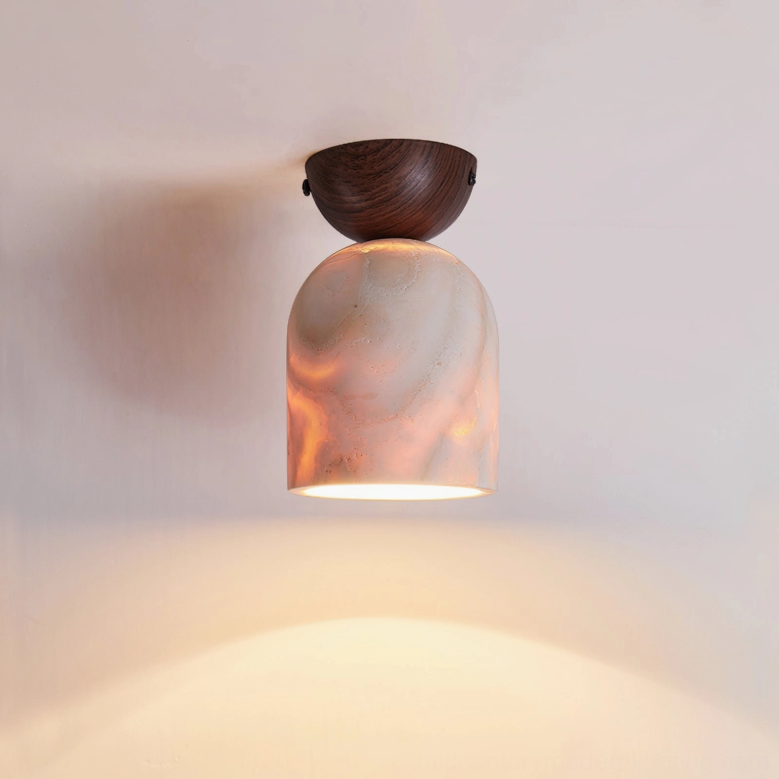 Glowing travertine pendant with dark wood cap and pink marble texture against light gray wall interior