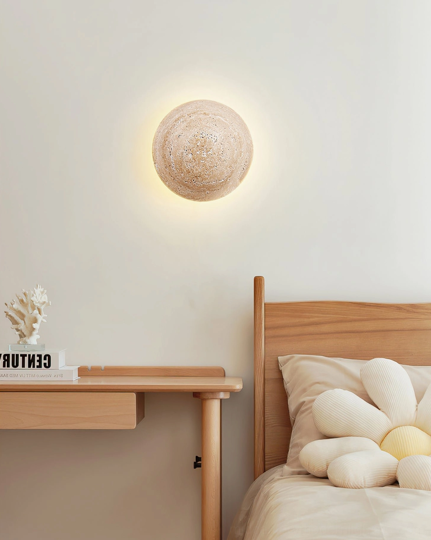 Yellow travertine sconce with warm light over wooden desk with decorative coral ornament accent
