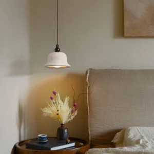 Bedside pendant lamp creating warm ambient glow in minimalist bedroom setting