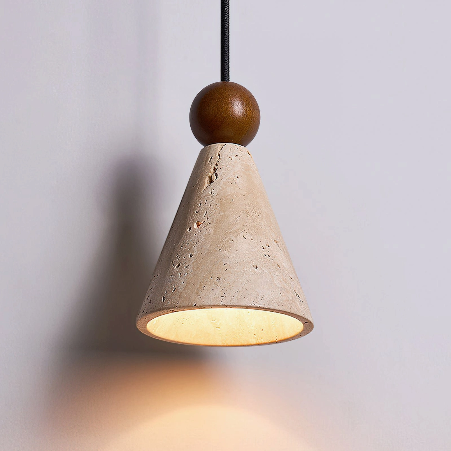 Canyon travertine pendant light lit from below showing warm amber glow and porous stone surface