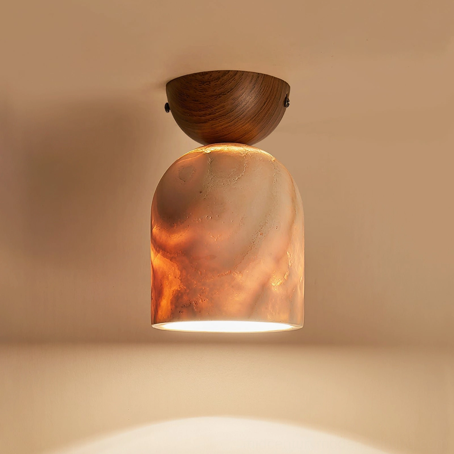 Illuminated travertine lamp with dark wood cap and orange marbled glowing shade on warm brown wall