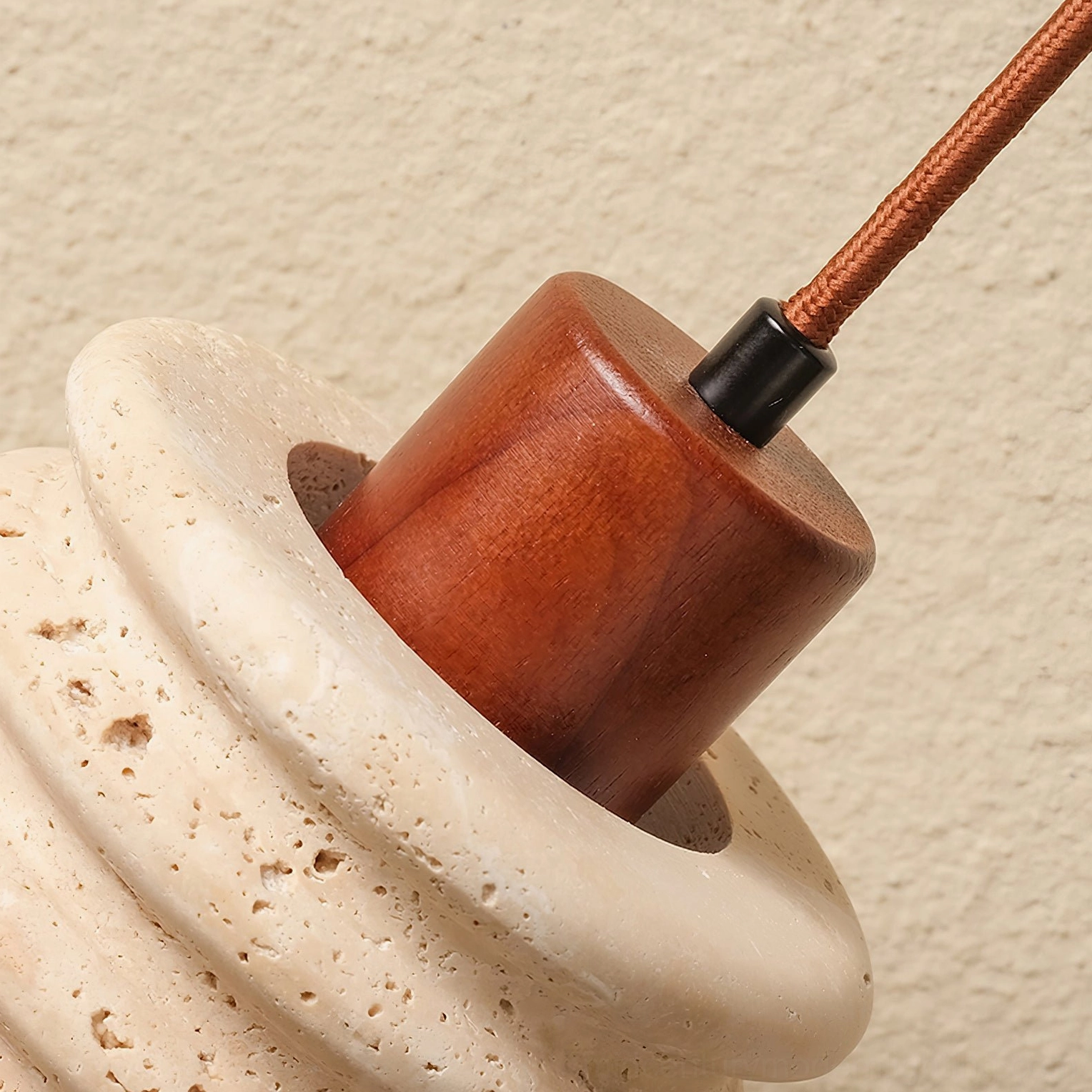 Connection detail between travertine shade and walnut wood ceiling canopy with brown fabric cord