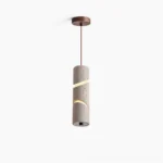 Travertine sculptural pendant lamp with spiral light cutouts shown in overhead studio view, revealing intricate carved pattern and natural stone texture