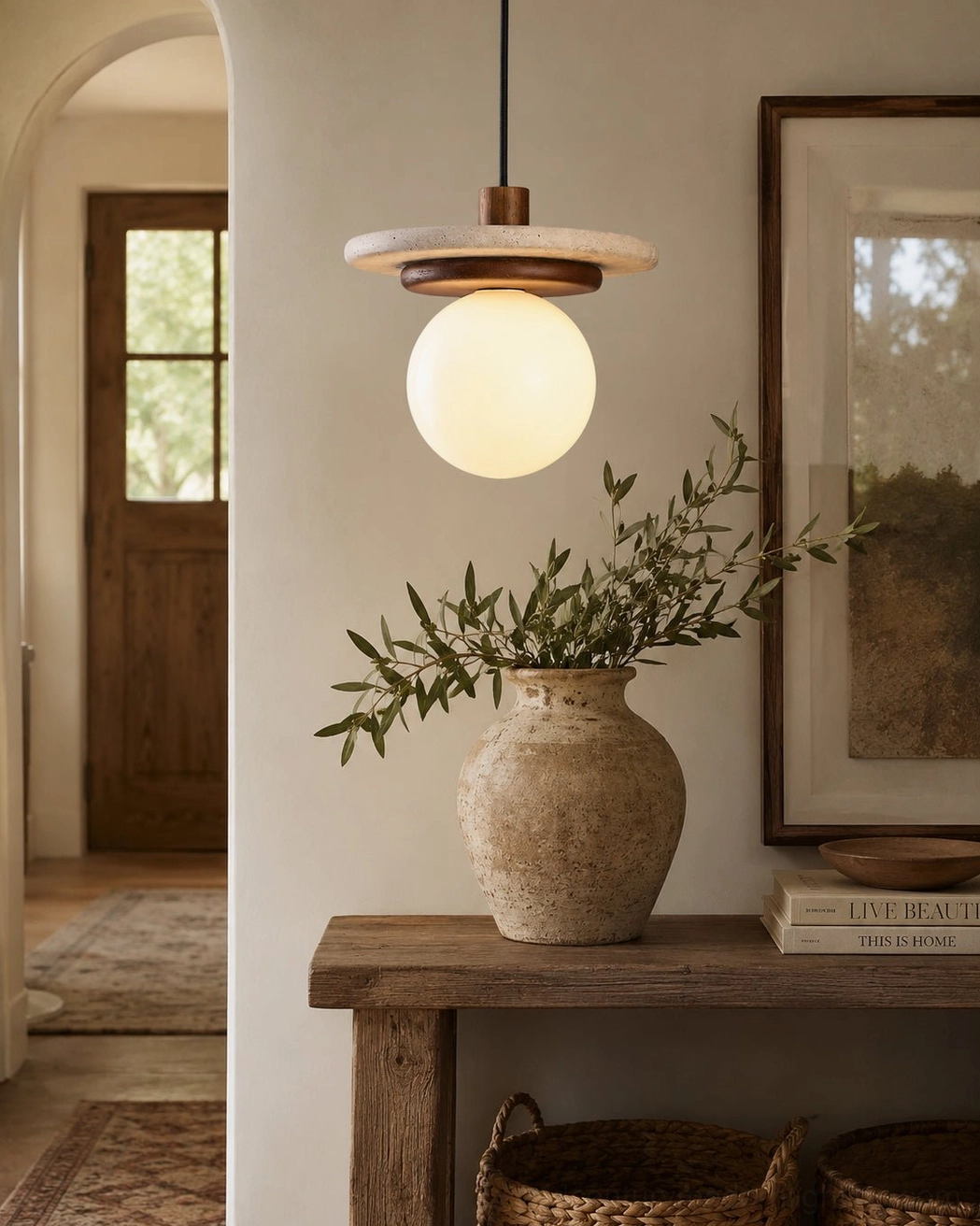 Travertine pendant light with ceramic vase and wall art in minimalist wabi-sabi entryway console area