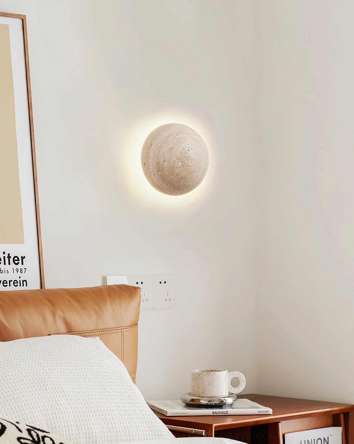 Minimalist travertine wall sconce next to leather bedside chair in contemporary bedroom corner