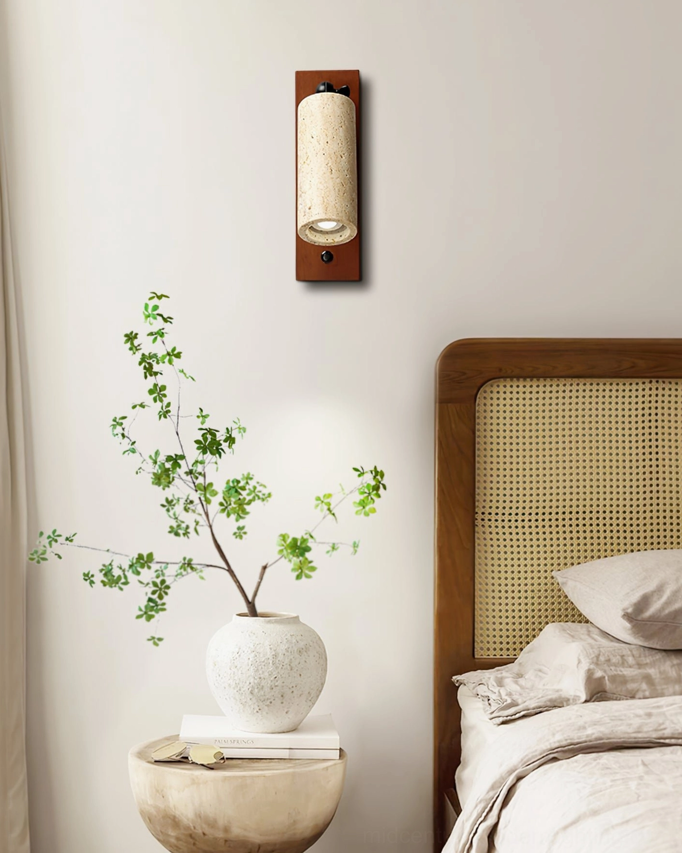 Travertine wall sconce in minimalist bedroom with green plant and dark brown backplate against window wall