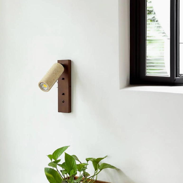 Side wall view of travertine sconce with indoor green potted plant and minimalist rustic dark brown base