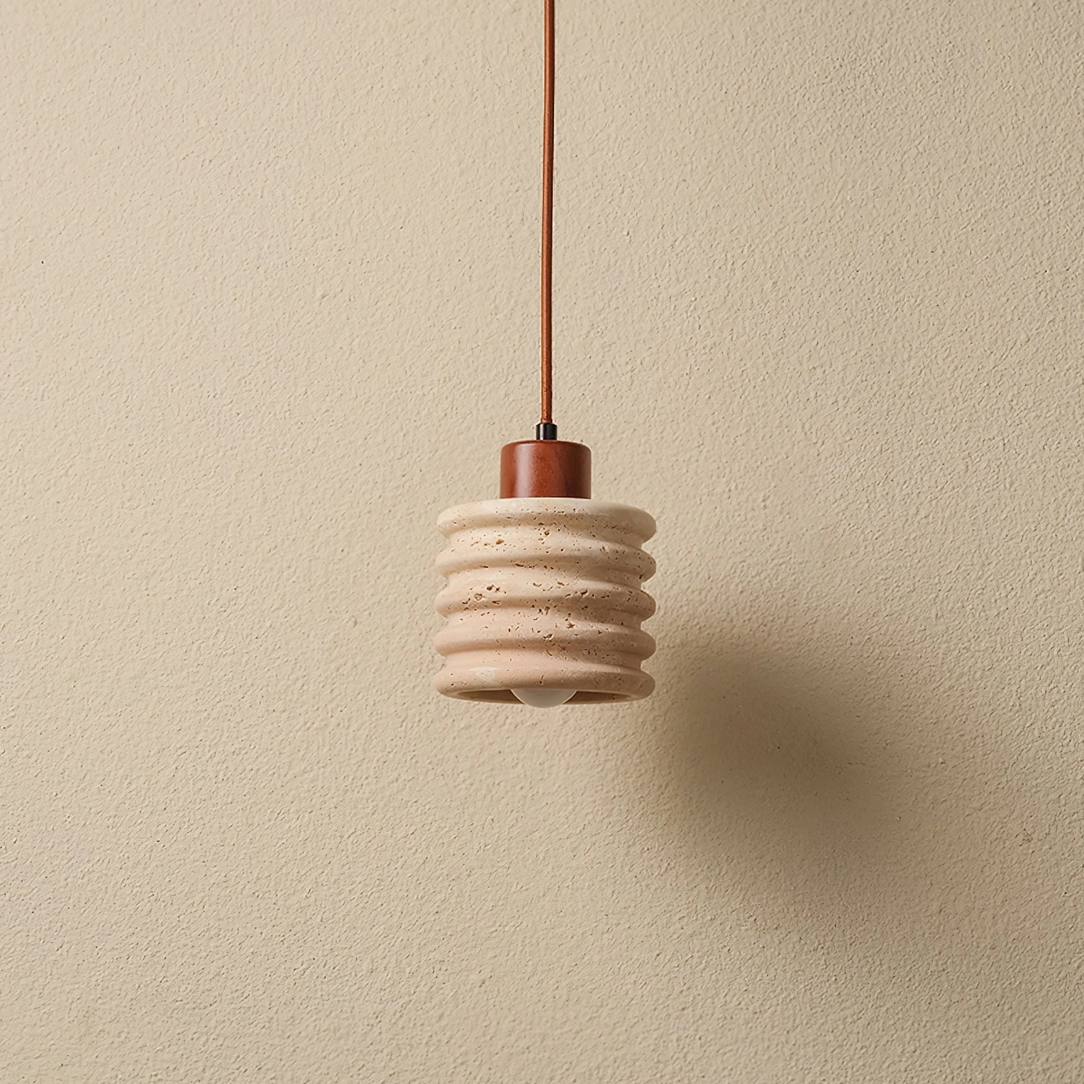 Side view of natural travertine pendant with minimalist wabi-sabi aesthetic and walnut wood fixture
