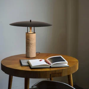 Travertine table lamp displayed on round wooden side table with open books and warm ambient lighting, home decor styling