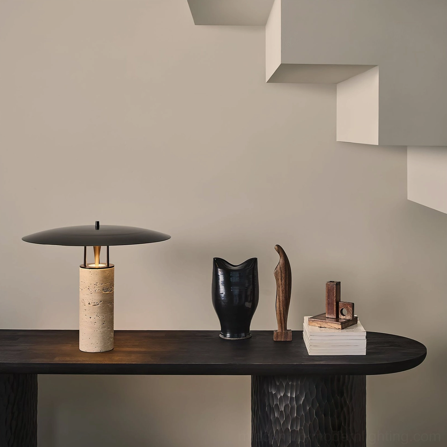 Travertine table lamp on entryway console with black and wooden decorative objects, minimalist entrance design