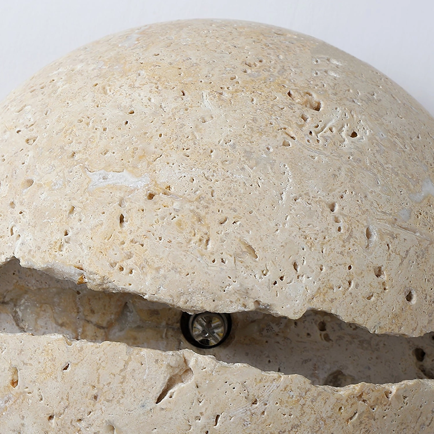 Close-up macro view of travertine stone porous texture and crack detailing on round wall lamp