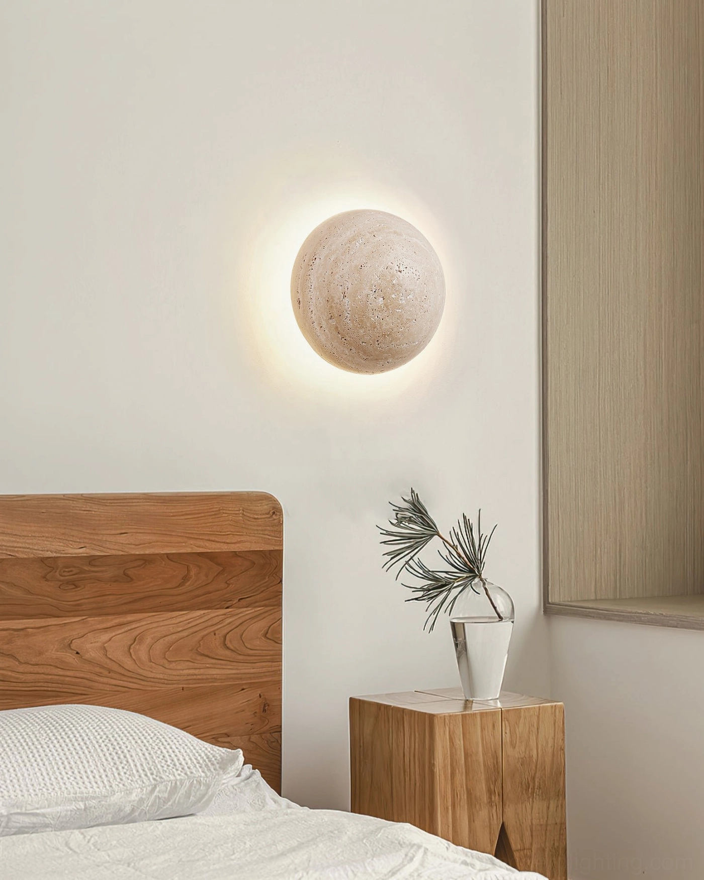 Travertine wall lamp providing soft illumination next to wooden side table with potted plant