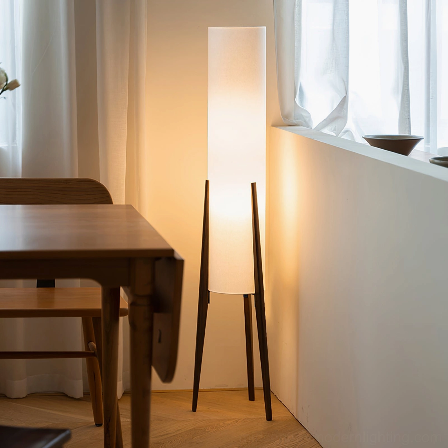 Tripod floor lamp in dining area corner with wooden table and chairs, mid-century modern aesthetic