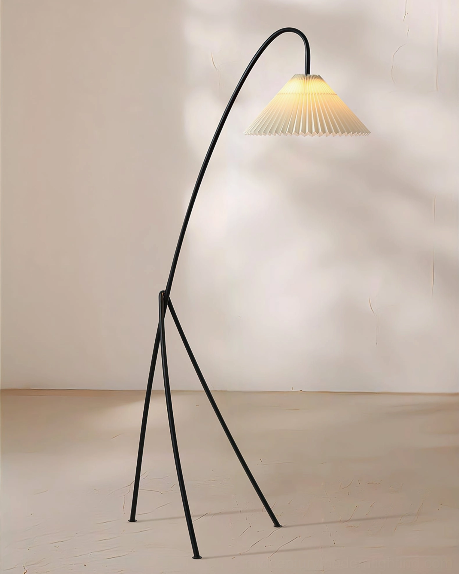 Black metal arc tripod floor lamp stand in minimalist studio setting, side angle view showcasing geometric tripod base and curved arm structure