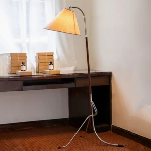 Tripod floor lamp in home study environment beside wooden desk, demonstrating warm ambient lighting in mid-century interior setting
