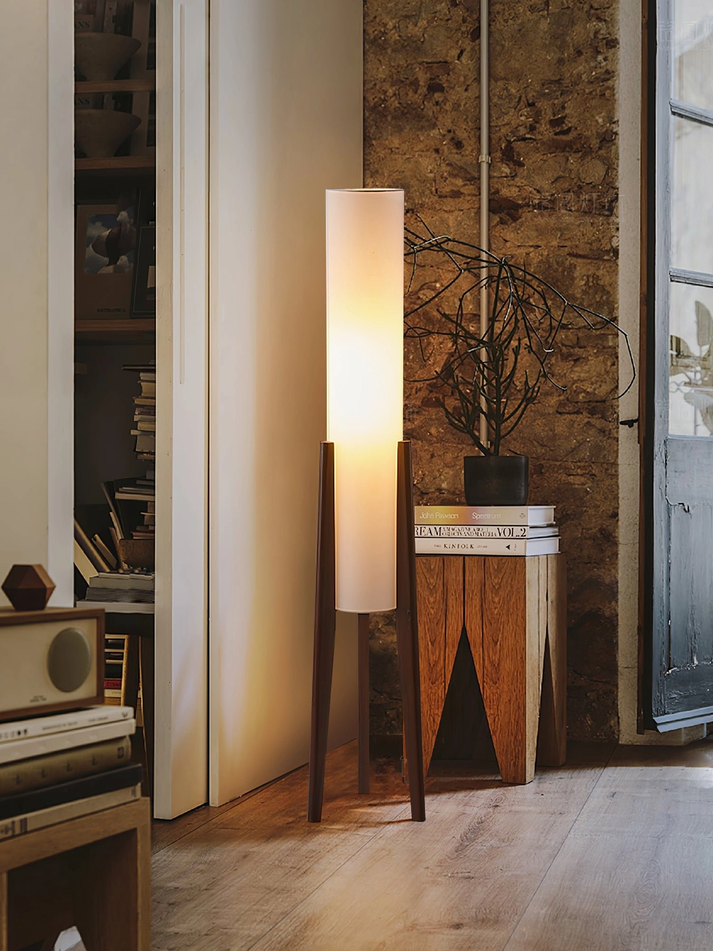 Mid-century modern tripod floor lamp in vintage study entryway with brick wall and wooden decor