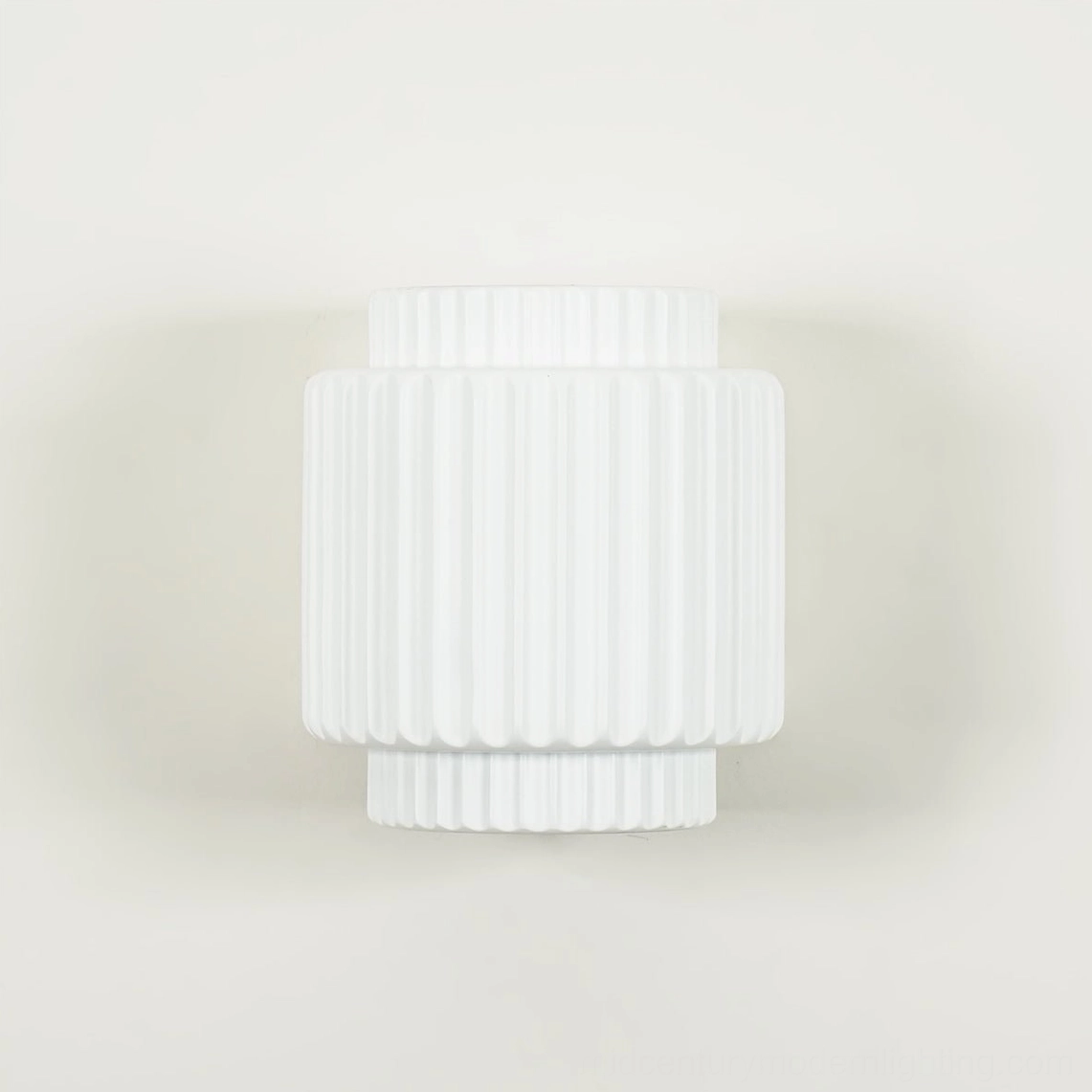 Tristan white wall lamp frontal view displaying dual-aperture lighting system and geometric ribbed surface texture