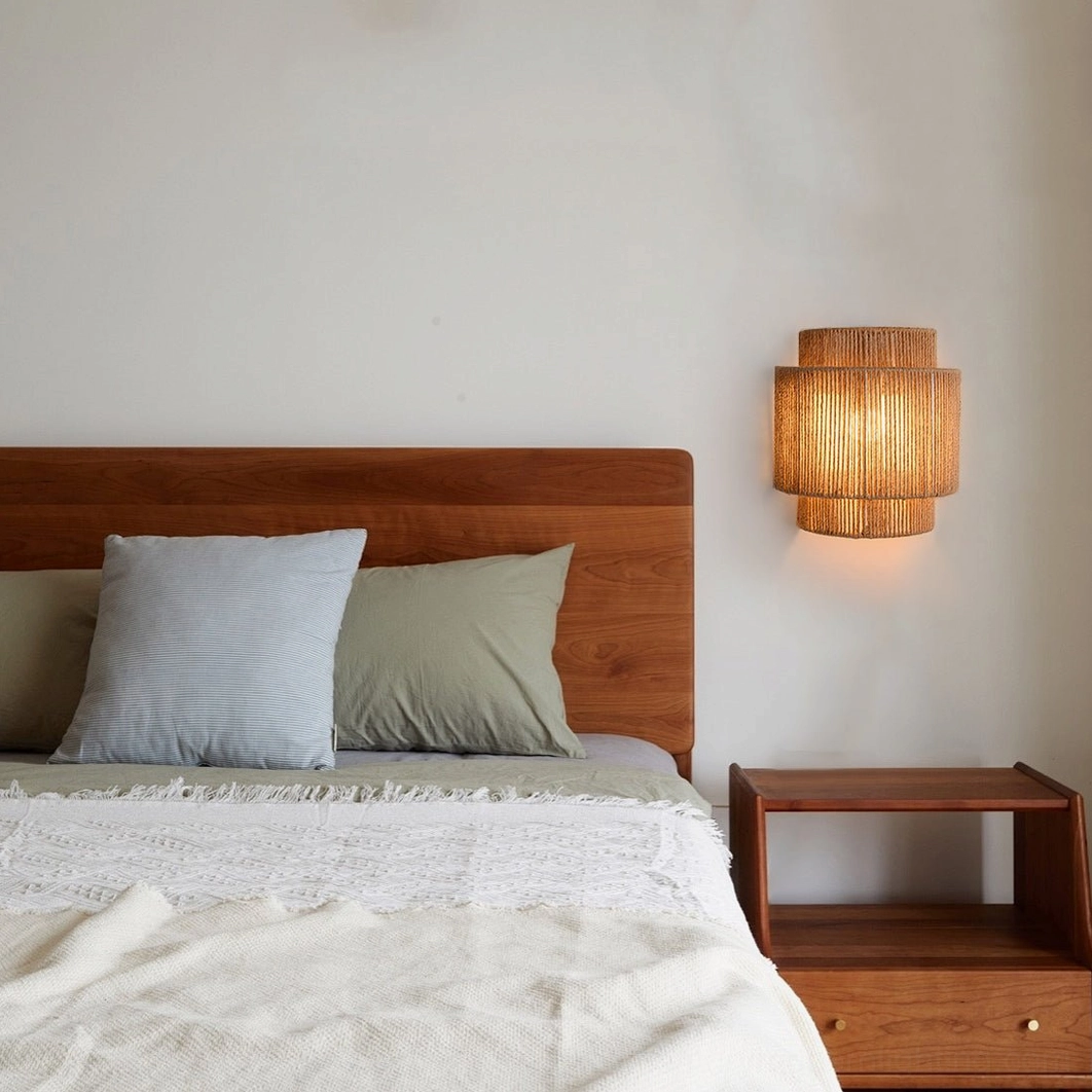 Natural rope wall-mounted sconce illuminating bedroom space with wooden bed and rustic nightstand
