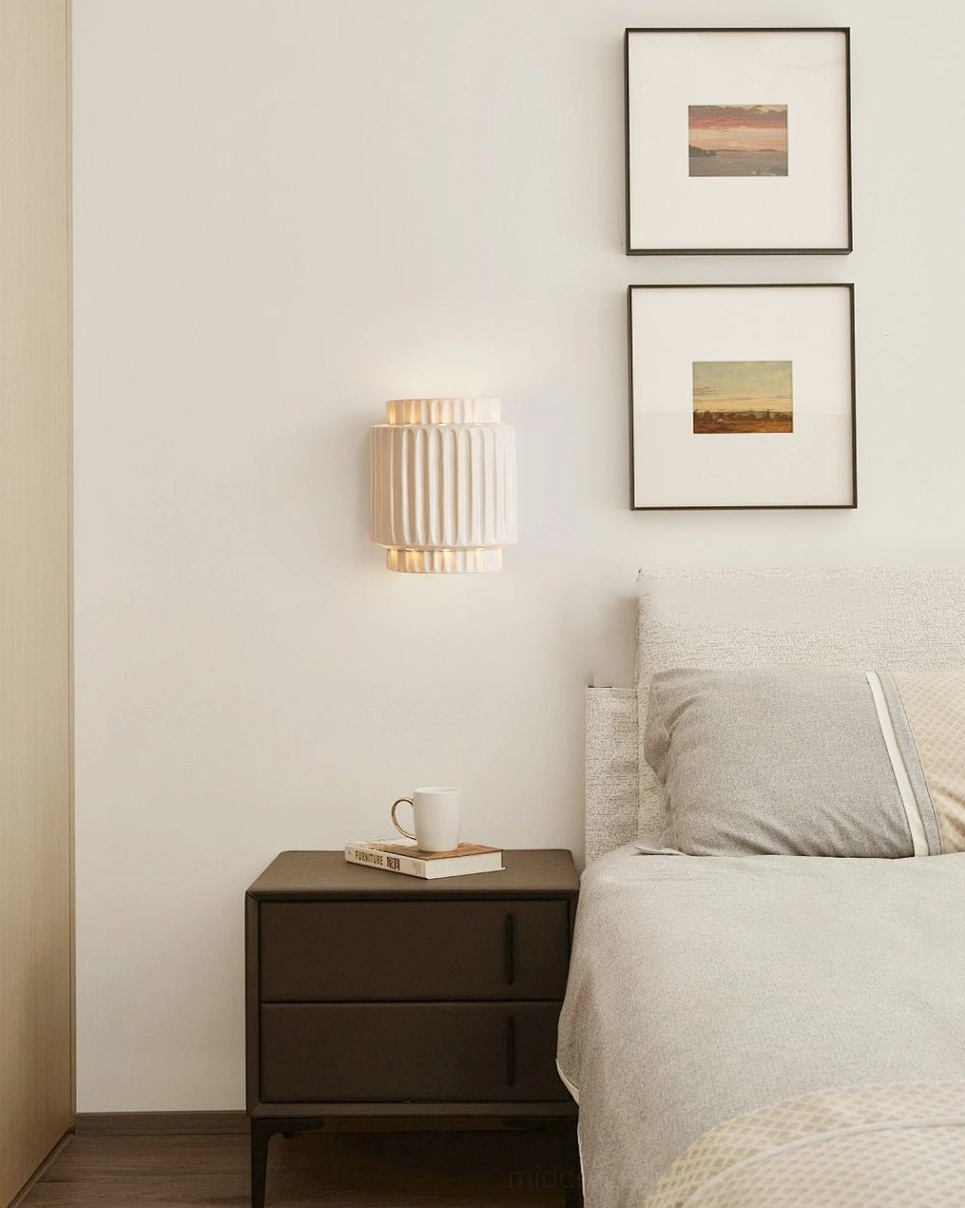 Tristan mid-century modern wall lamp mounted in contemporary bedroom interior with dark nightstand and framed artwork