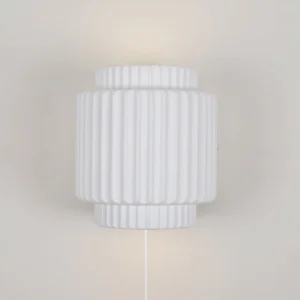 Tristan plug-in wall lamp mounted on plain indoor wall showing power cord and vertical fluted texture detail