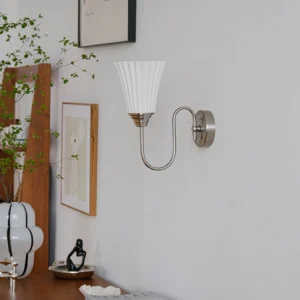 Brushed nickel wall sconce installed in vintage home study - soft ambient lighting with pleated ceramic shade
