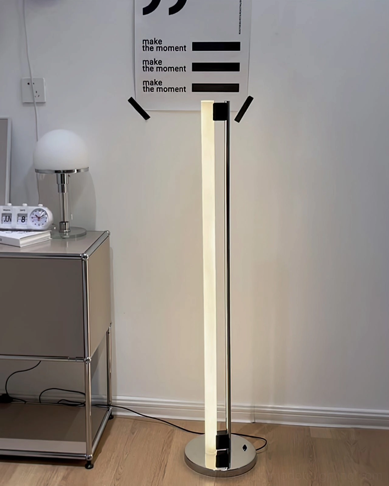 Tube LED floor lamp beside minimalist accent chair demonstrating space-saving vertical form factor