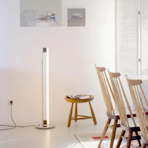 Tube LED floor lamp creating warm ambient lighting in modern dining room with wooden chairs and neutral interior