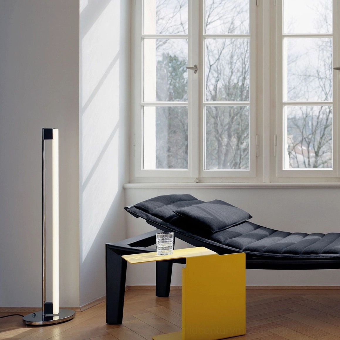 Chrome tube floor lamp positioned in contemporary home office creating sophisticated ambient lighting