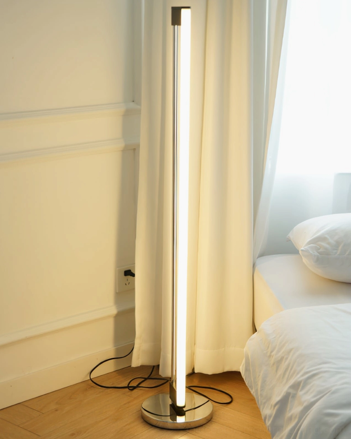 Chrome tube floor lamp positioned in industrial modern interior with exposed elements and metal accents