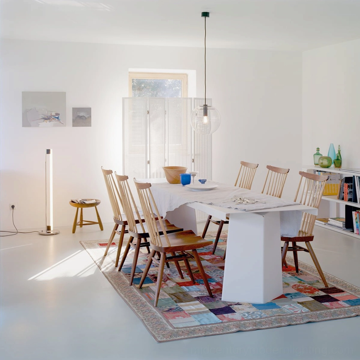 Tube LED floor lamp in bright dining room with patterned rug creating modern minimalist ambiance