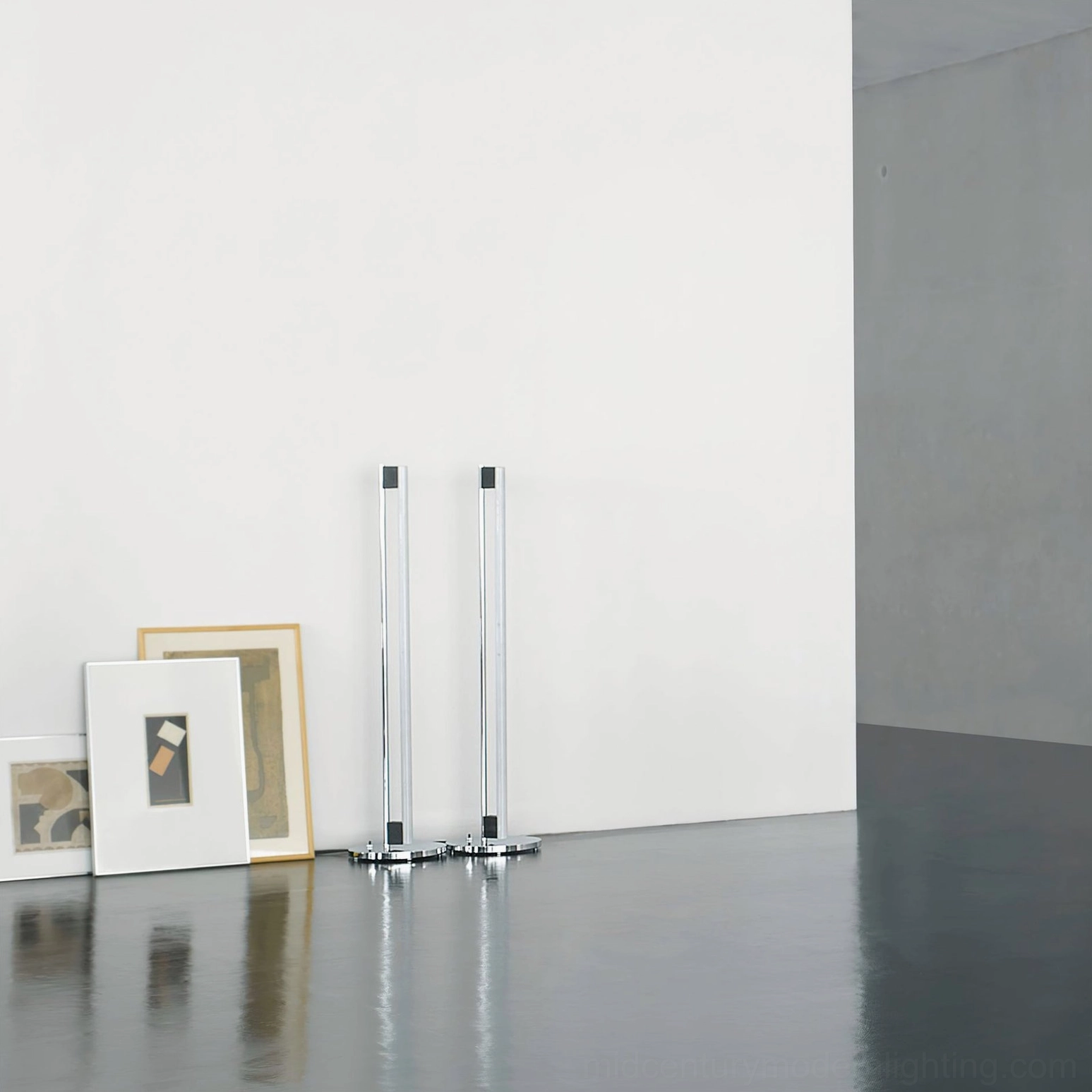 Unassembled chrome tube LED floor lamp bases on dark studio background showing assembly components