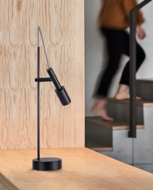Tubino black table lamp in Nordic minimalist interior setting with stairwell and wooden furniture