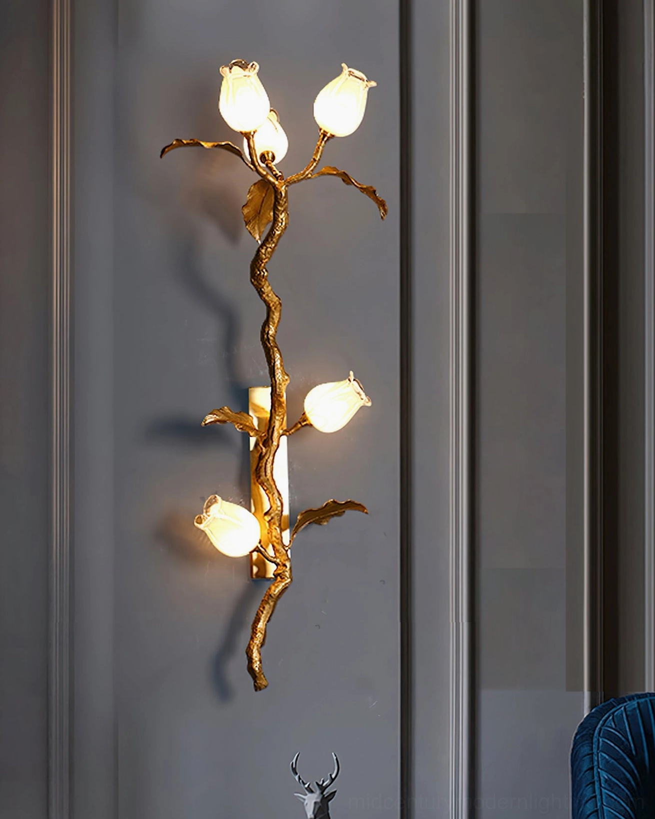 Tulip Branch Brass Wall Sconce front view with warm glowing lights against minimalist grey paneled wall background